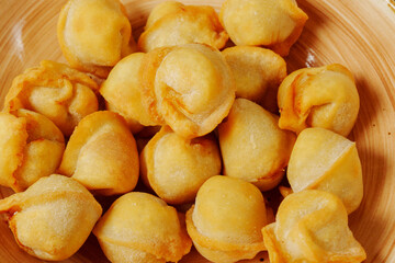 Golden dumplings arranged artfully in a wooden bowl, showcasing their crispy texture and inviting aroma on a sunny afternoon