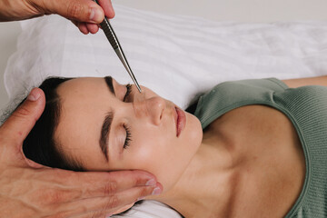 Post-surgery rhinoplasty care. Woman is having her nose taped after nose surgery. Preventing...