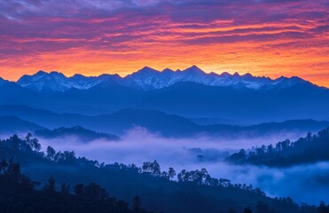 Obraz premium A breathtaking sunrise illuminates snow-capped peaks, casting vibrant colors over misty valleys as daybreak unfolds in the mountains