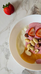 White plate with yogurt, strawberries, honey and nuts on a white marble table. High quality photo