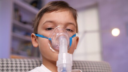 Young boy using inhaler for respiratory therapy at home