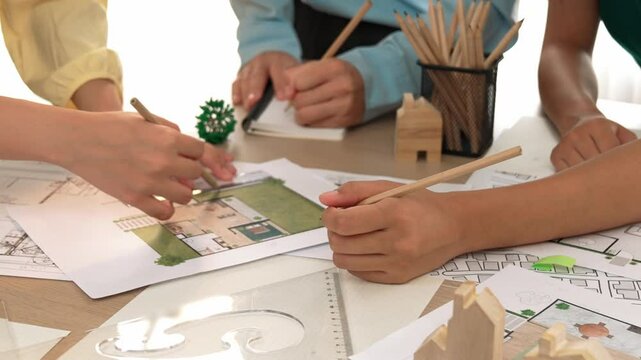 Smart architect and safety engineer discussion about building blueprint on table with architectural document, measurement tools and wooden block scatter around at modern office. Closeup. Delineation.