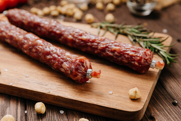 Smoked salami sticks on a wooden board with herbs, perfect for charcuterie boards and gourmet snacks