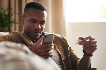 Black man, phone and online shopping with credit card on sofa for payment, banking or fintech at home. Young African, male person or shopper with debit on mobile smartphone for ecommerce at house