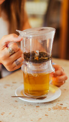 Plano detallde de una mano filtrando una Tisana herbal