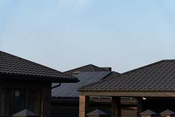 Several contemporary houses featuring solar panels on their roofs bask in the sunlight, showcasing sustainable energy solutions in a clear sky