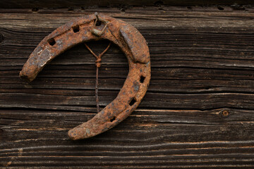 old rusty horseshoe hanging on a nail on a wooden wall