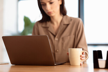 Serious Female Manager Using Laptop Reading Business News Having Morning Coffee Working From Home