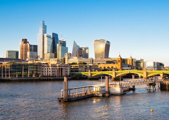 A vibrant cityscape of London featuring modern skyscrapers along the River Thames, reflecting the warm glow of sunset.