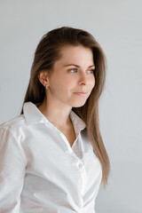 Young smiling confident business woman wearing white top shirt casual clothes looking side isolated on grey background studio portrait. Vertical shot. Lifestyle concept. A professional office worker