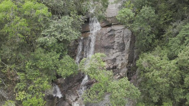 Drone camera pans up as drone flies along Cachoeira do Barata waterfall in Tepequem, Roraima, Brazil