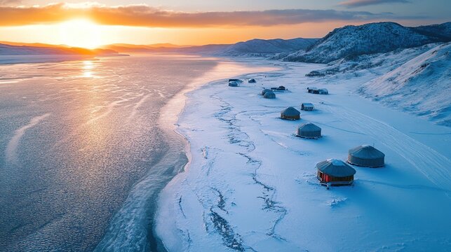 Snowy landscape with yurts by a frozen river.