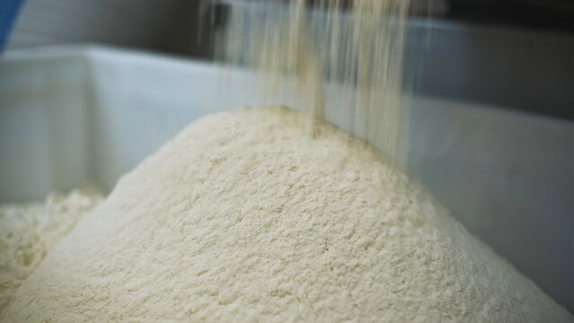 Close-up of crumbling flour. Clip. Industrial production of pure flour for cooking. Industrial flour and baking factory