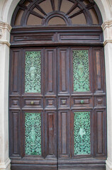 Obraz premium Antique Wooden Door with Decorative Glass Panels. A close-up of a vintage wooden door featuring intricate green stained glass panels and detailed carvings.