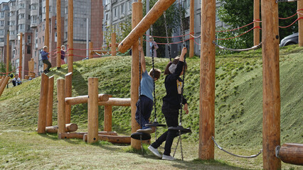 Children play on playground near house. Clip. Children play on modern wooden playground. Wooden playground with children playing near houses