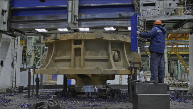 Worker with remote control and rotating lathe. Stock clip. Worker with control panel for factory metalworking machines. Turning carousel machine for metalworking - Powered by Adobe