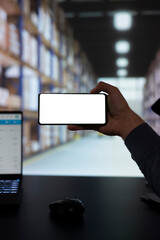 Industrial worker dealing with cargo inventory and logistics, working on quality control and looking at white screen on phone. Warehouse employee using smartphone with blank layout.