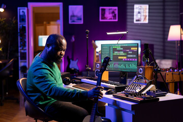 Musical producer prepares to record tunes on acoustic instrument, working in his personal home studio to record a soundtrack. Sound composer recording guitar music, editing with mixing console.