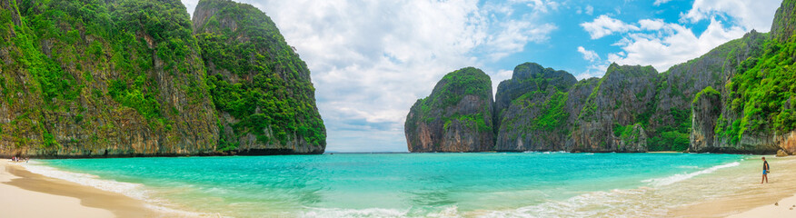 Panoramic view of tropical sandy beach Maya Bay with turquoise water ocean on Phi Phi islands, Krabi, Thailand. Male traveler on idyllic beach with mountains and green plants. Travel and tourism