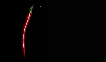 A pod of red hot pepper on a black background