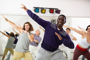 Positive adult African American man practicing modern vigorous dance movements in group dance class