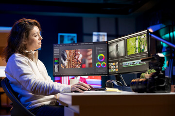 Smiling video editor works for independent production company checking stills on camera gallery before inputting music, dialogues, graphics and effects over raw footage, editing clip for final project