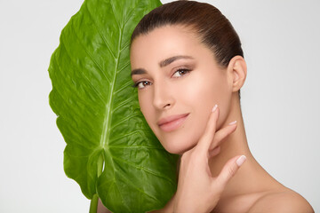 Woman embracing natural skincare with large green leaf