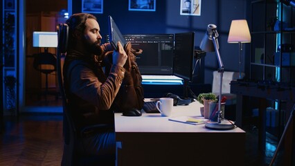 Software designer finishing remote job shift, packing backpack, leaving office after finishing coding project. IT professional putting laptop in bag, sitting up from desk chair, camera B