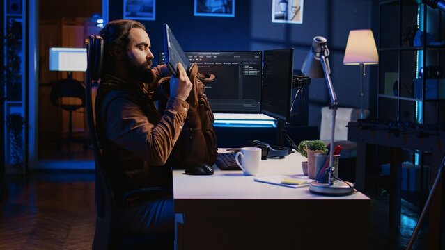 Software designer finishing remote job shift, packing backpack, leaving office after finishing coding project. IT professional putting laptop in bag, sitting up from desk chair, camera B