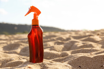 Bottle of sunscreen cream on sand at beach