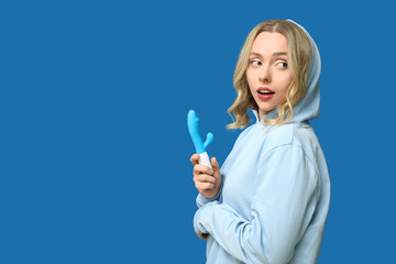 Beautiful young woman with vibrator on blue background