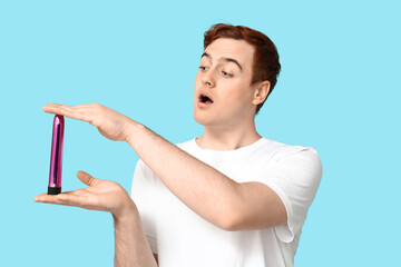 Surprised young man with vibrator on blue background