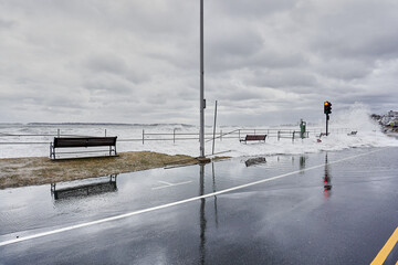 Storm surge causing water to go over seawall and flood the sidewalk and streets.