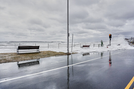 Storm surge causing water to go over seawall and flood the sidewalk and streets.