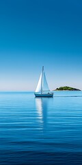 Fototapeta premium A sailboat sails past a small island on a calm blue sea.