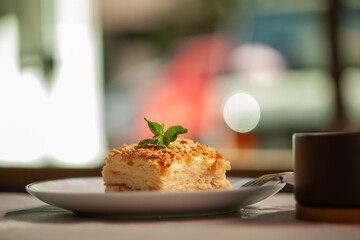 Delectable napoleon cake with mint on a cafe table, against a blurred background. Creamy layers promise a burst of freshness. Perfect for bakery or restaurant themes