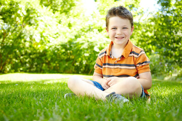 Boy, child and outdoor portrait on grass, forest adventure and countryside meadow for development. Male person, happy kid and travel to France for exploring, relax and healthy growth in environment