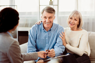 Insurance Concept. Happy senior couple consulting with female agent at home, signing papers