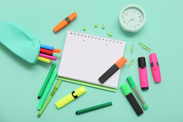 Alarm clock and different stationery on turquoise background. Top view