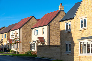 New build homes in UK, on a sunny morning, with vivid blue sky.