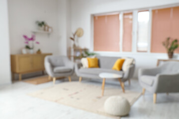 Blurred view of living room with sofa, armchairs and window
