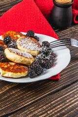 Cottage cheese pancakes with fresh blackberries on a white flat white plate