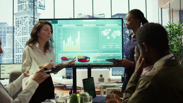 Coworkers engaging in a problem solving meeting at a corporation, using an interactive board to visualize data and develop solutions for complex business challenges. Analysis presentation. Camera B.