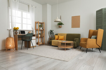 Interior of living room with workplace, sofa and armchair