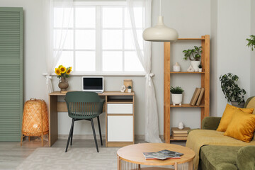 Interior of living room with workplace, sunflowers in vase and shelf unit