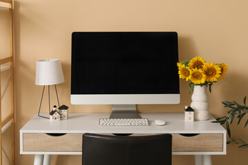 Blank computer monitor and vase and sunflowers on desk in office