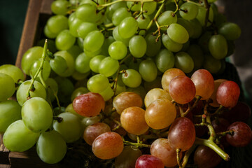 Wooden box with sweet ripe grapes on green background, closeup