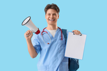 Male medical intern with megaphone and blank clipboard on blue background