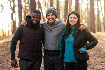 Fototapeta premium Happy adventurous international friends posing over blue tent in the middle of forest