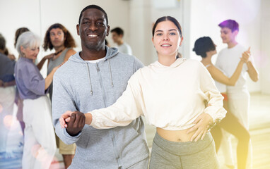 Active couple of dancers learns a partner dance, studying at a dance school in a group class